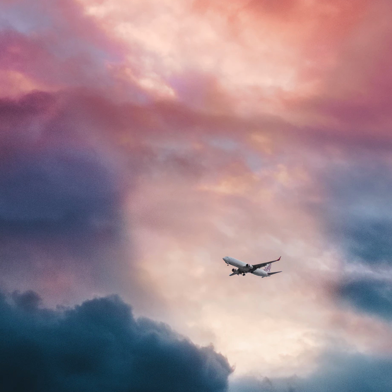 airplane flying among pink and blue clouds